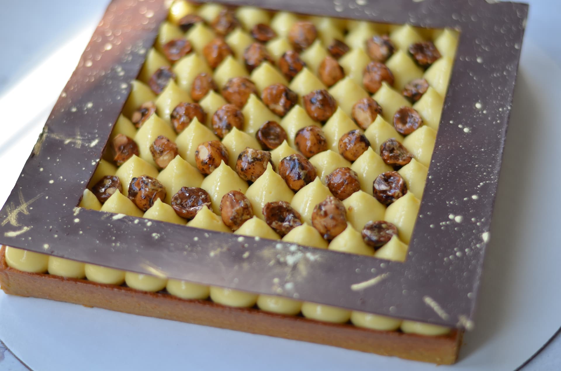 Square chocolate and hazelnut tart with piped cream